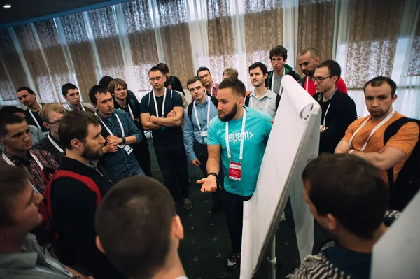 Engineers gathered around Mikalai at a flip chart during a Q&A session